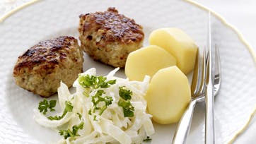 Frikadeller med stuvet hvidkål og kartofler på hvid tallerken