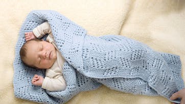 Lyseblåt tæppe svøbt om baby