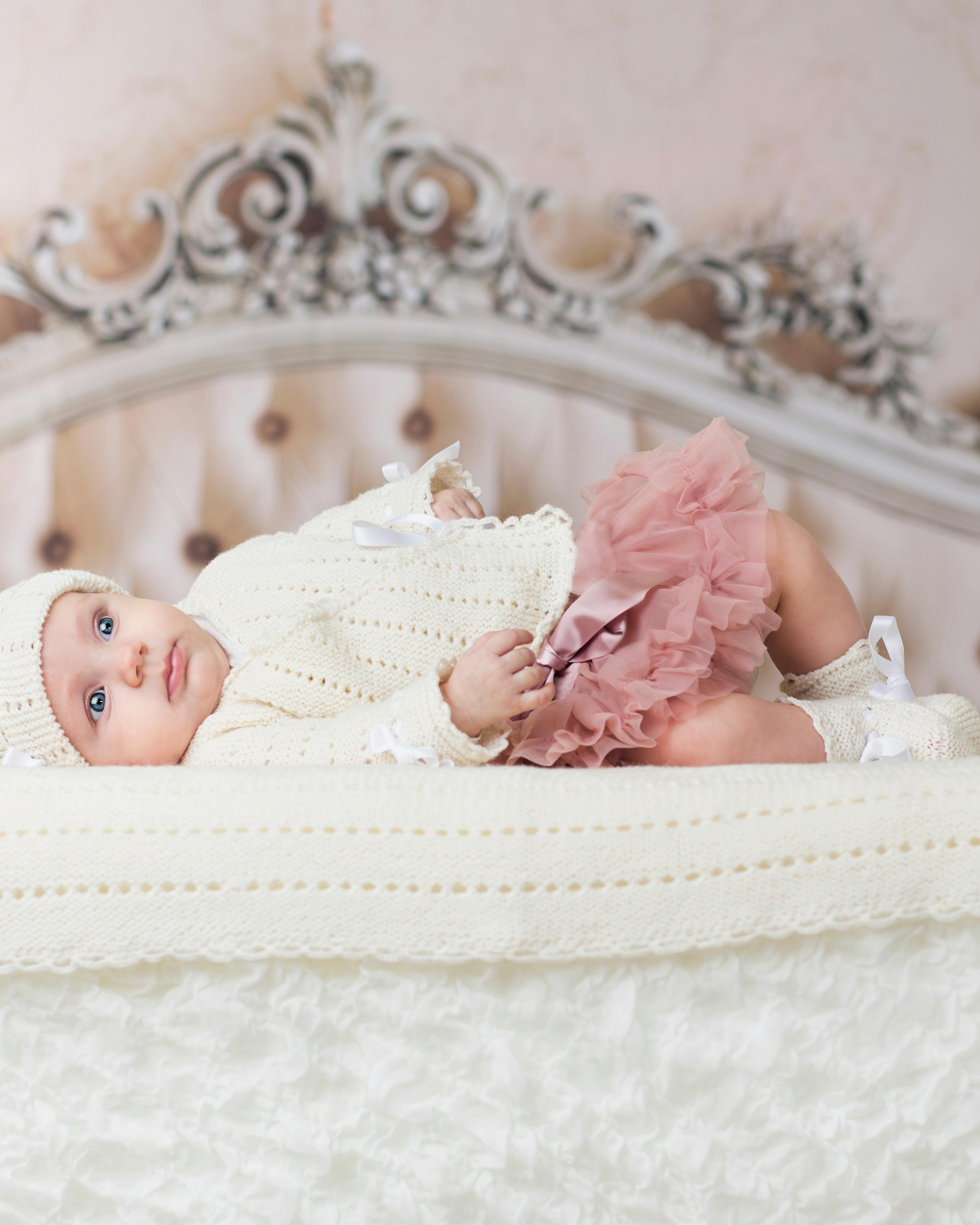 Baby ligger på send med strikket tæppe