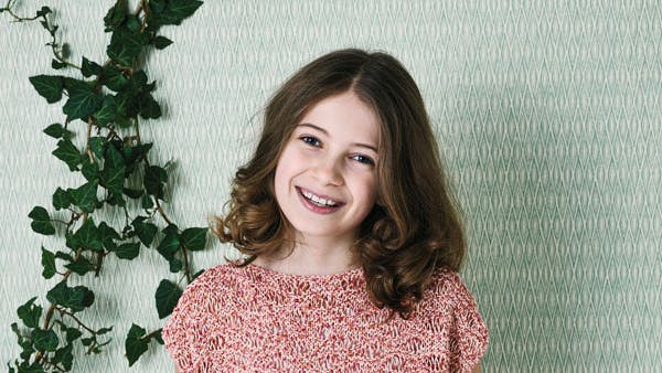 Pige står med strikbluse i bølgemønster