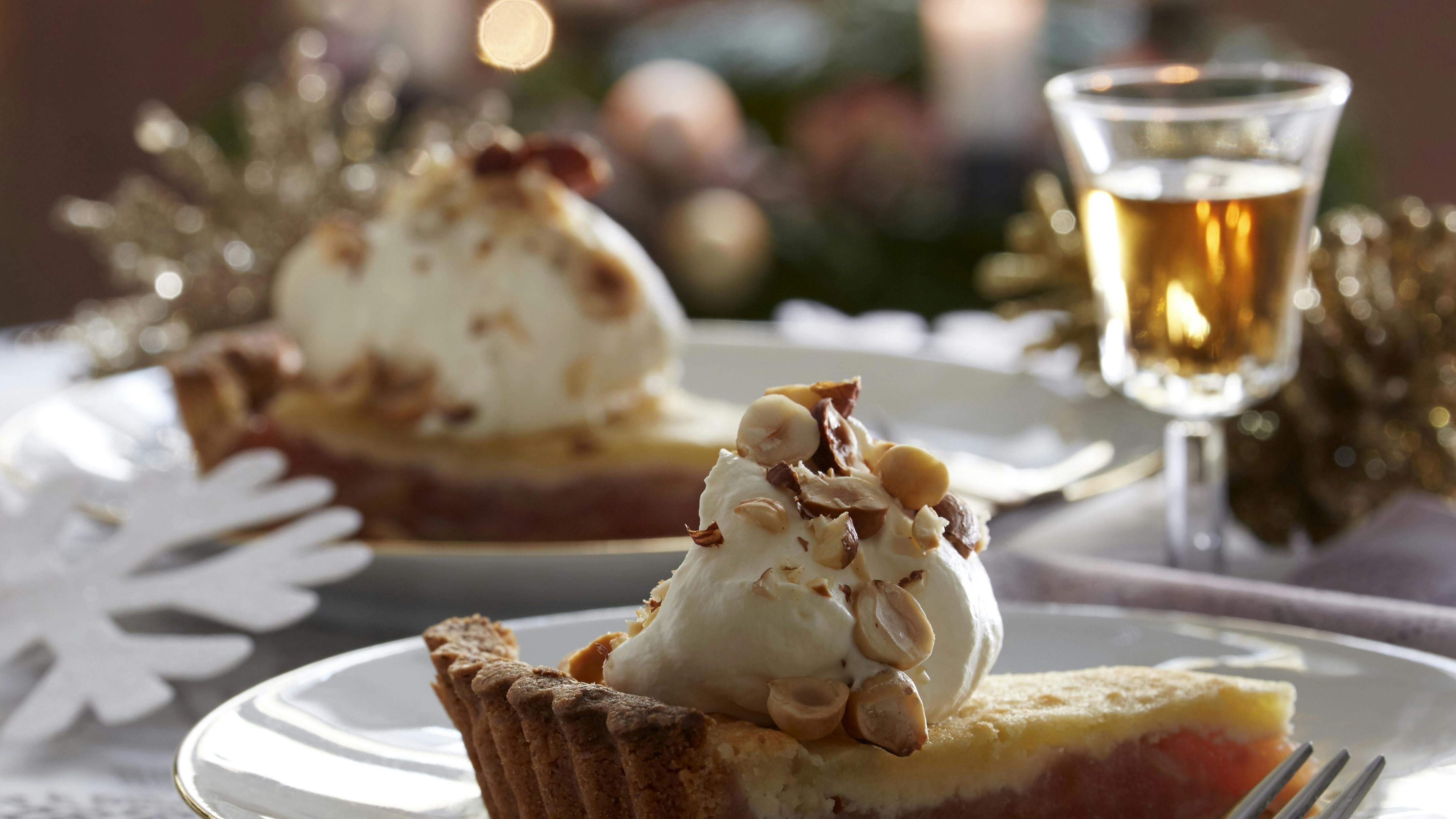 Skøn æbletærte med marcipanlåg bagt med hakkede nødder i tærtebunden. Tærten serveres med flødeskum med nødder på toppen.