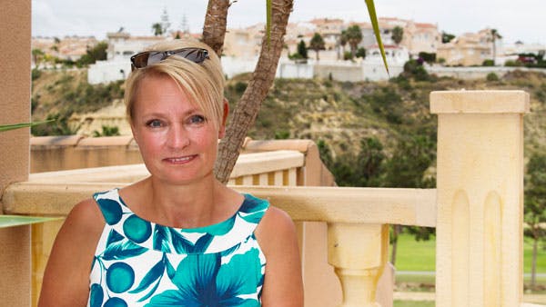 Leddegigt: Kvinde sidder på terrasse med palme i baggrund