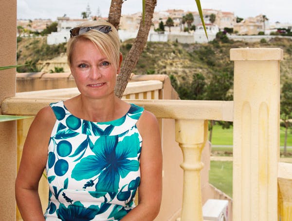 Leddegigt: Kvinde sidder på terrasse med palme i baggrund  