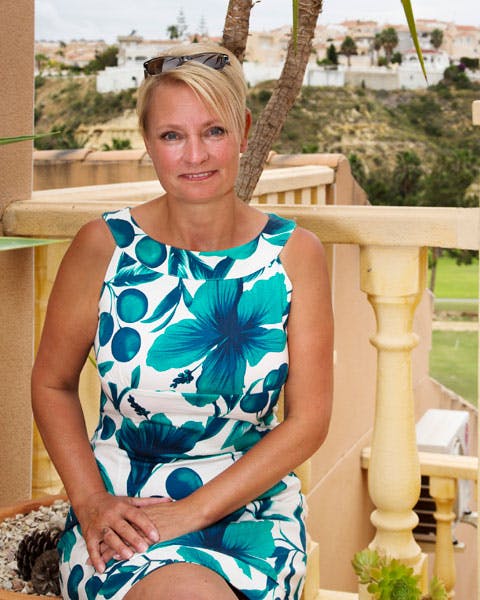 Leddegigt: Kvinde sidder på terrasse med palme i baggrund