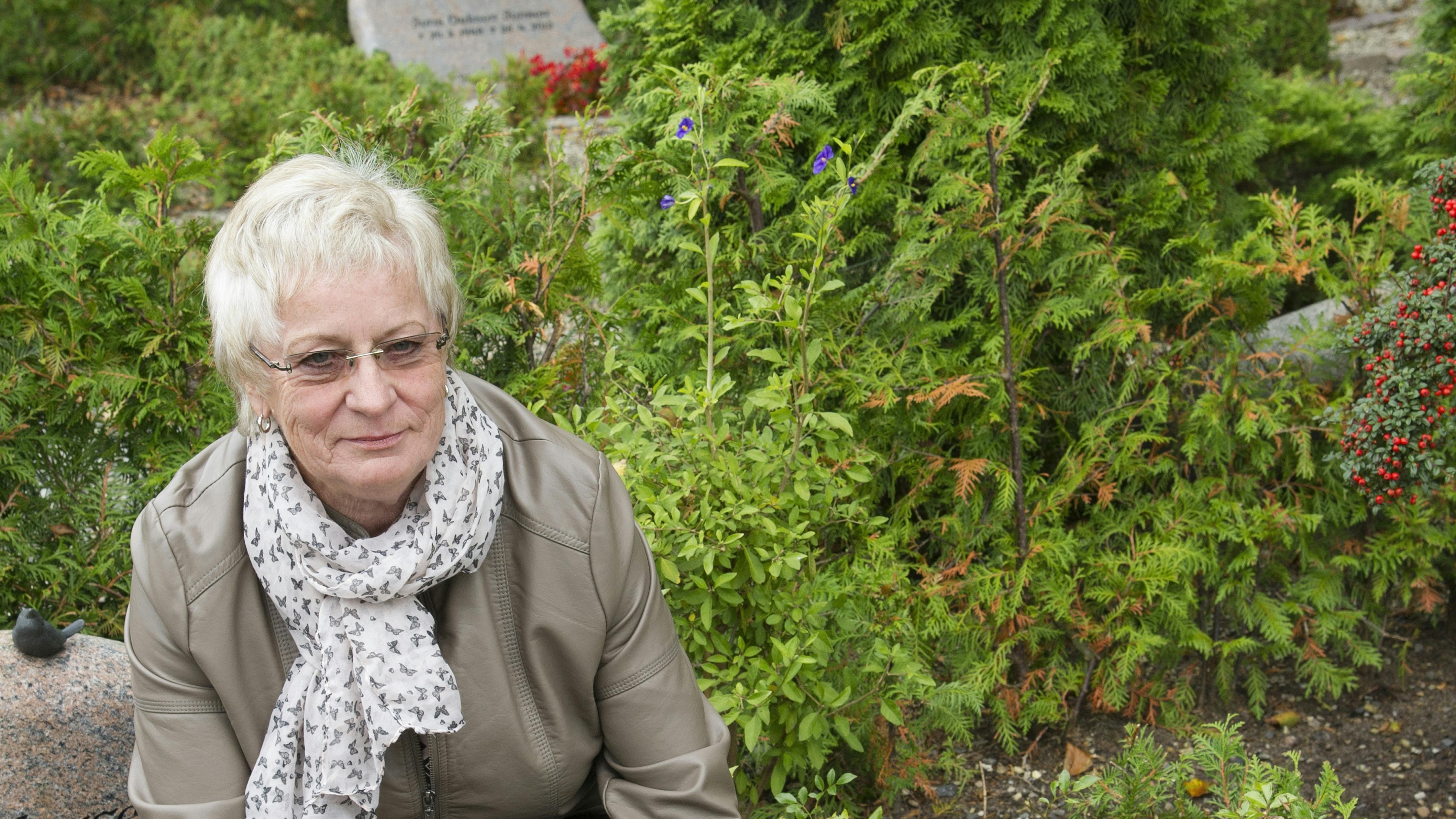 Dame sidder ved gravsten