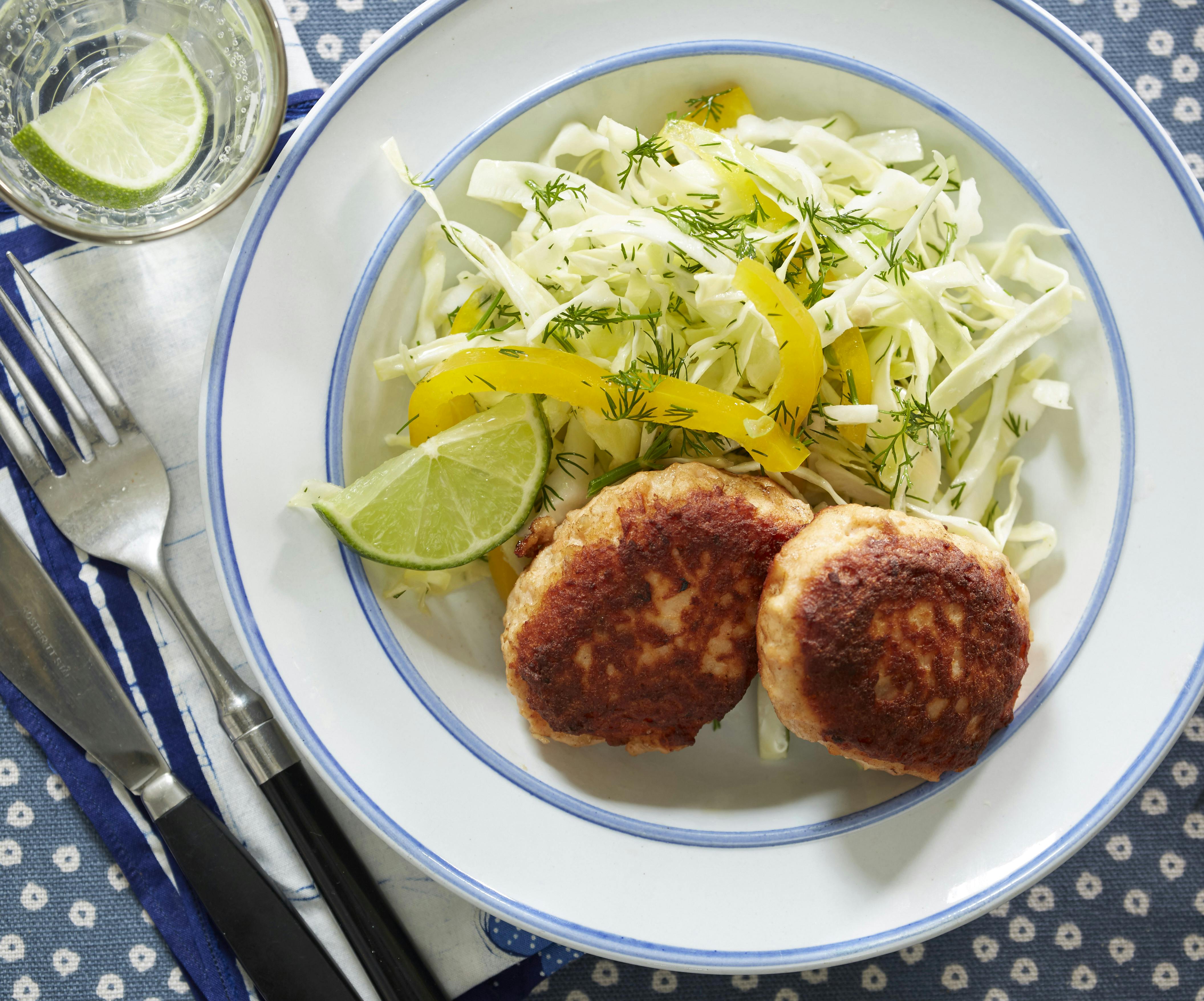 Fiskefrikadeller af laks og kartoffel serveret med salat af hvidål, peberfrugt og forårsløg 