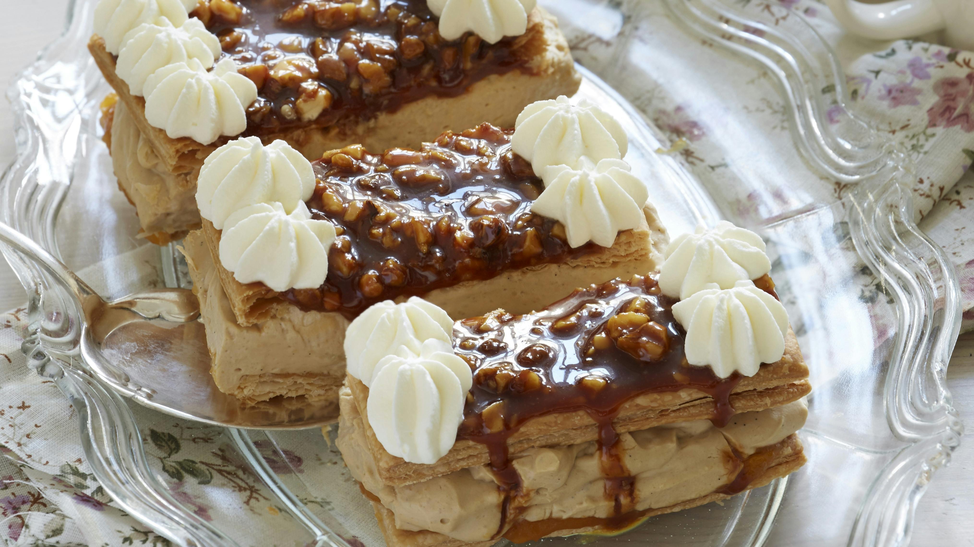 Flødekage bestående af to butterdejsbunde, der er lagt sammen med mokkacreme og pyntet med karamelmasse med valnødder og flødeskum
