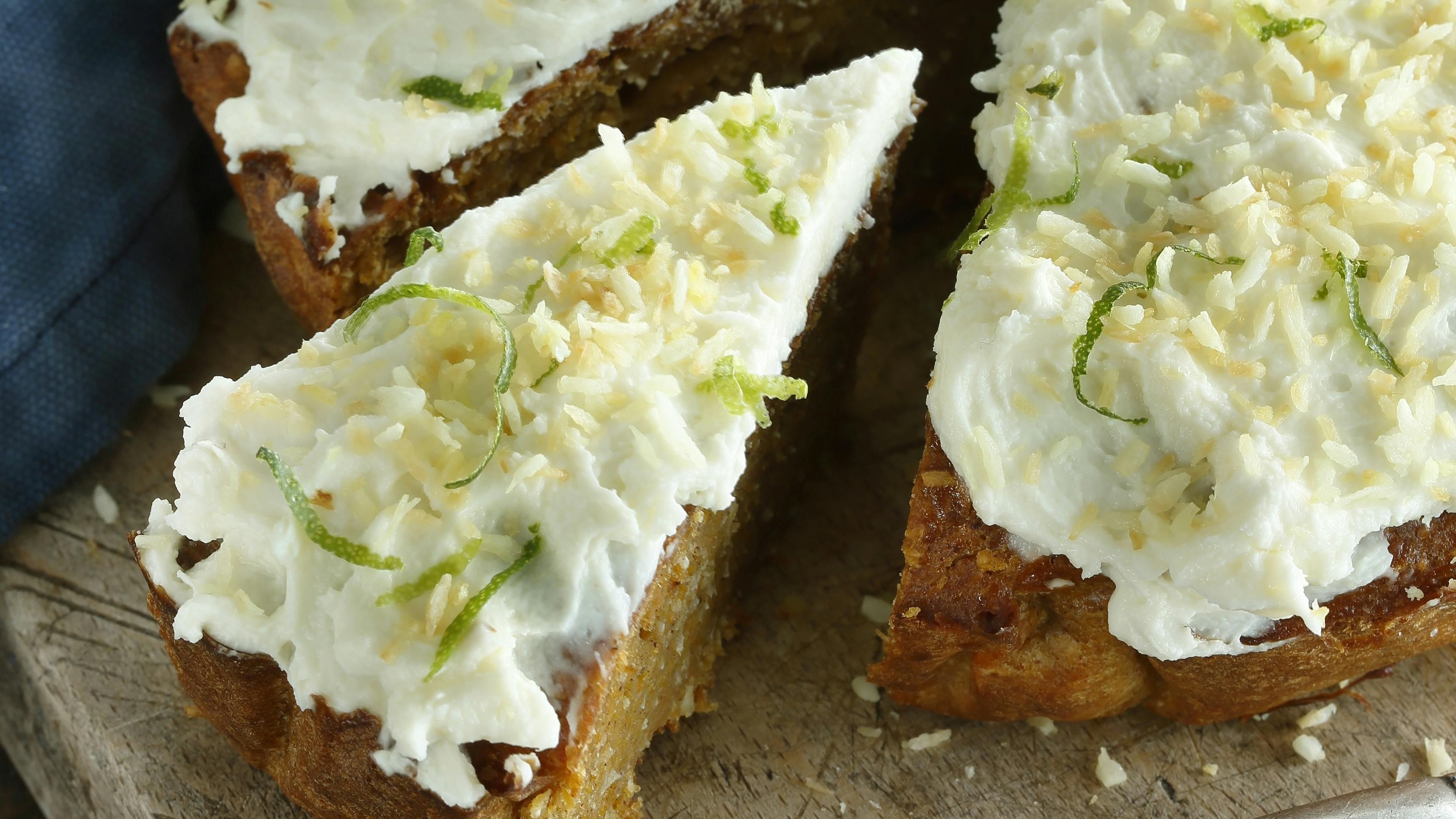 Gulerodskage med kokosmel toppet med en ostecreme smagt til med lime og vanilje og drysset med ristet kokos..