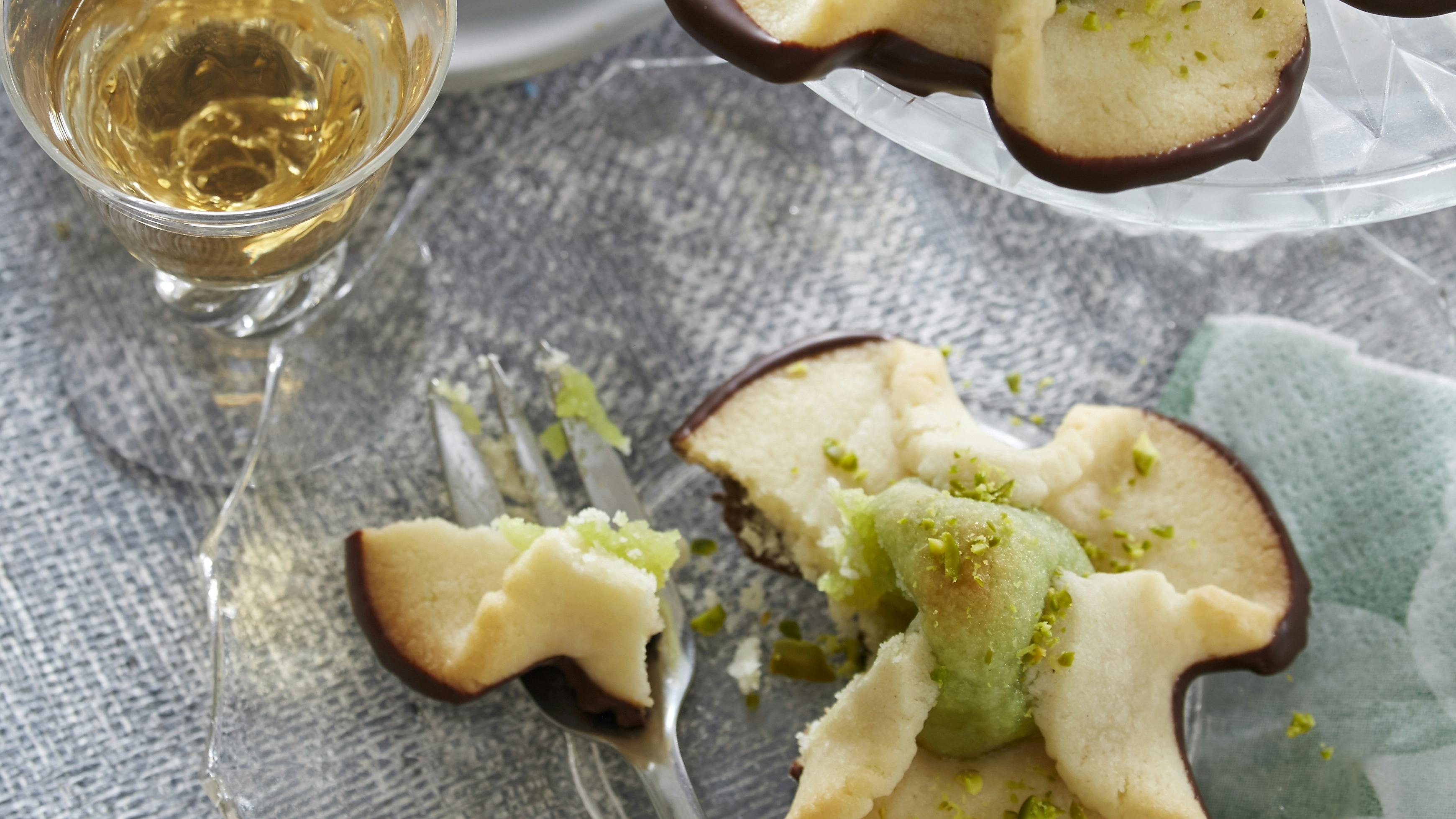 Napoleonshatte af mørdej omkring kerne af marcipan og pistaciemasse. På toppen hakkede pistacienødder og i bunden chokolade