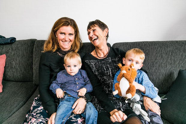 Knæk cancer. To damer sidder i sofa med børn på skødet. 