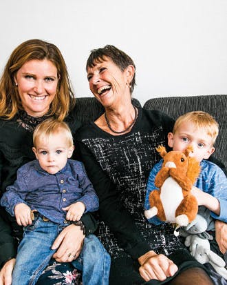 Knæk cancer. To damer sidder i sofa med børn på skødet.