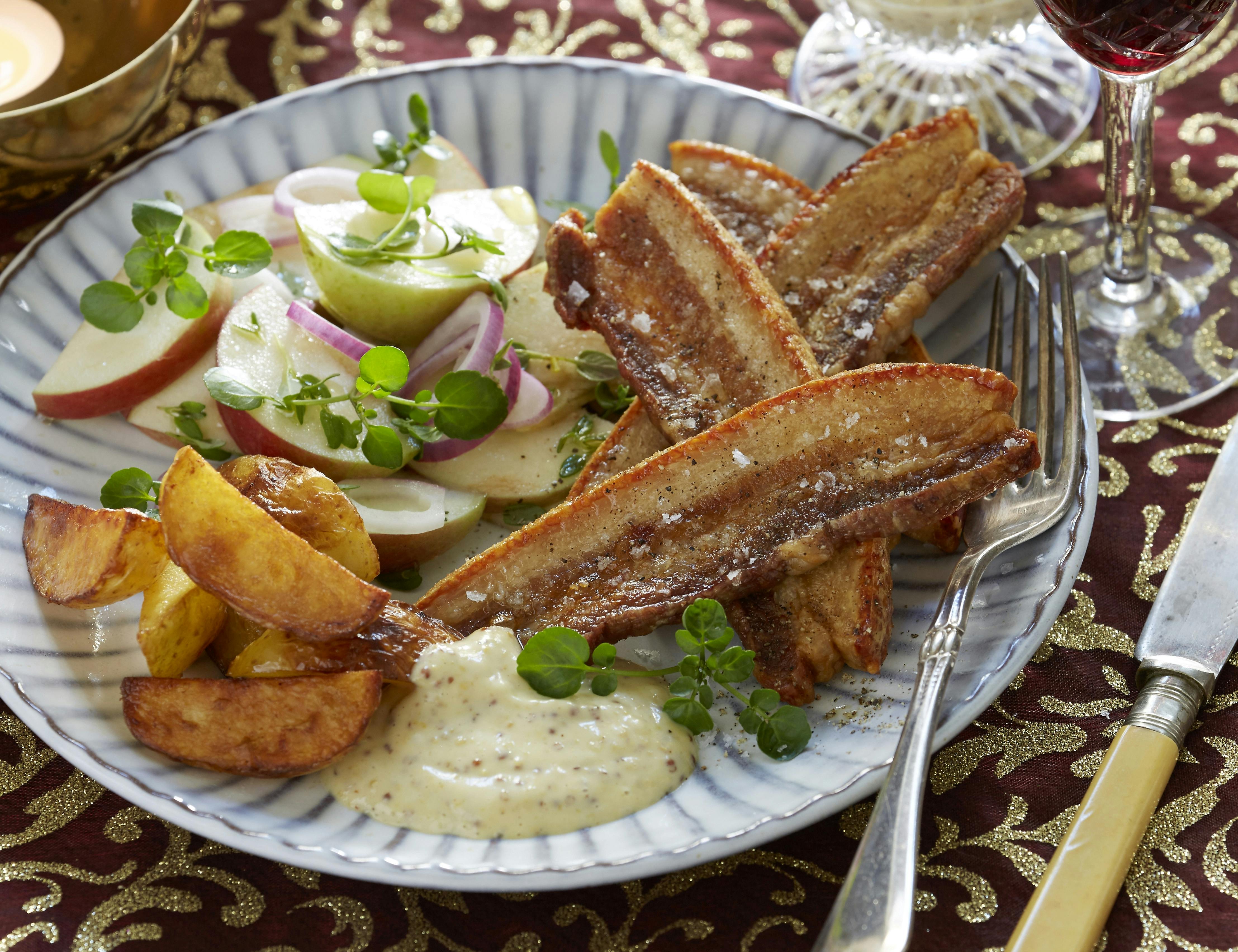 Flæsk og kartoffelbåde stegt i ovnen og serveret med en sennepsdip og salat med æble og løg