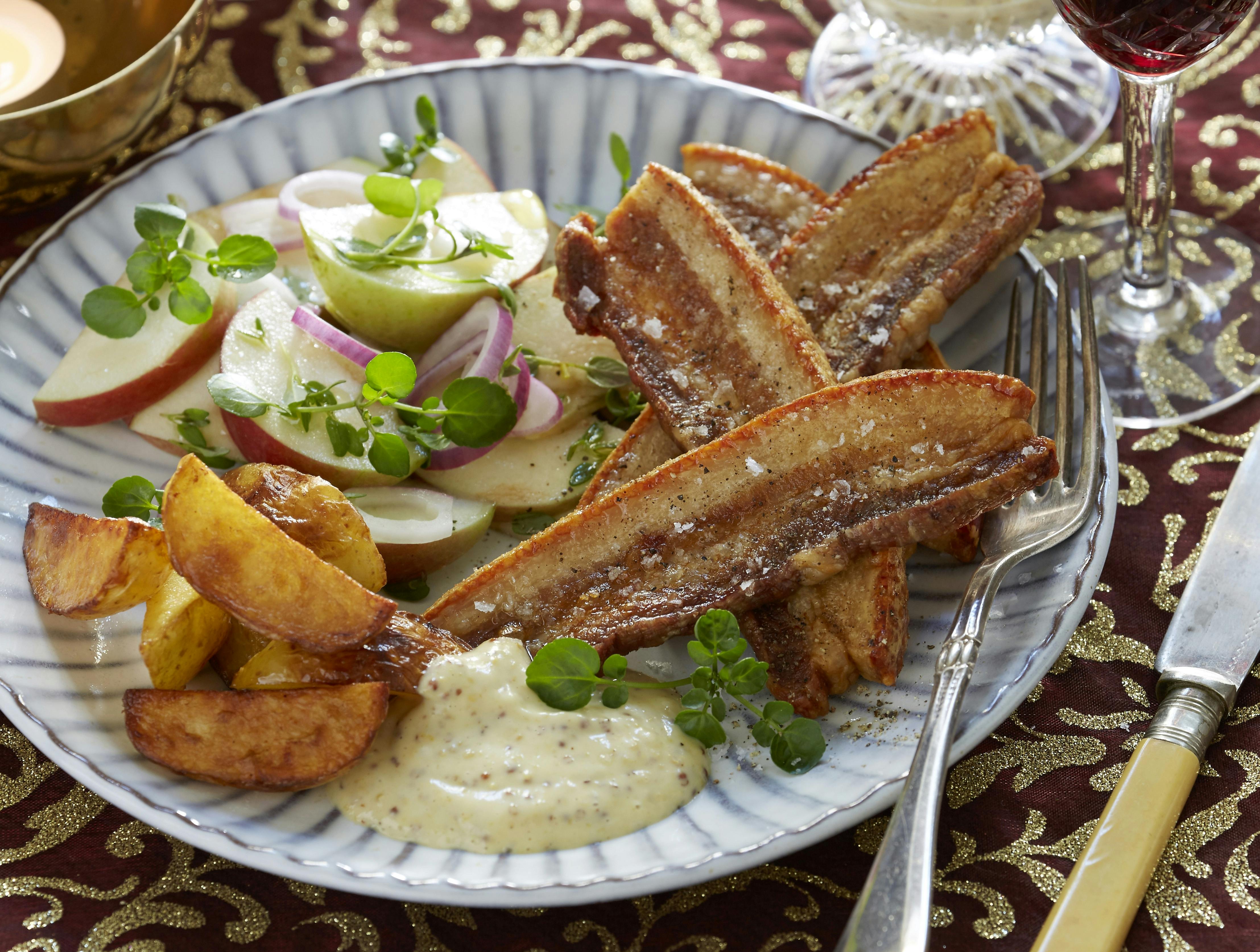 Flæsk og kartoffelbåde stegt i ovnen og serveret med en sennepsdip og salat med æble og løg