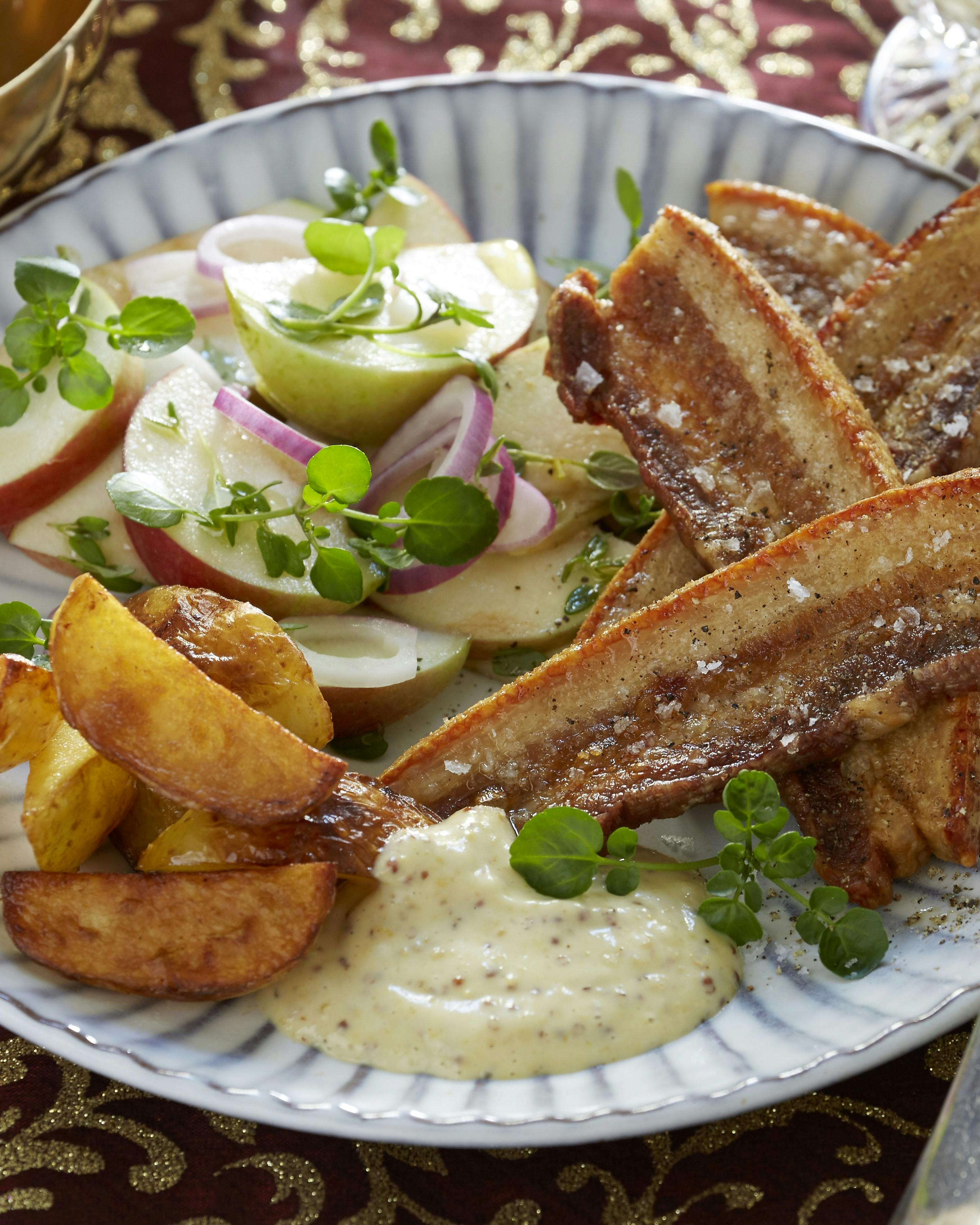 Flæsk og kartoffelbåde stegt i ovnen og serveret med en sennepsdip og salat med æble og løg