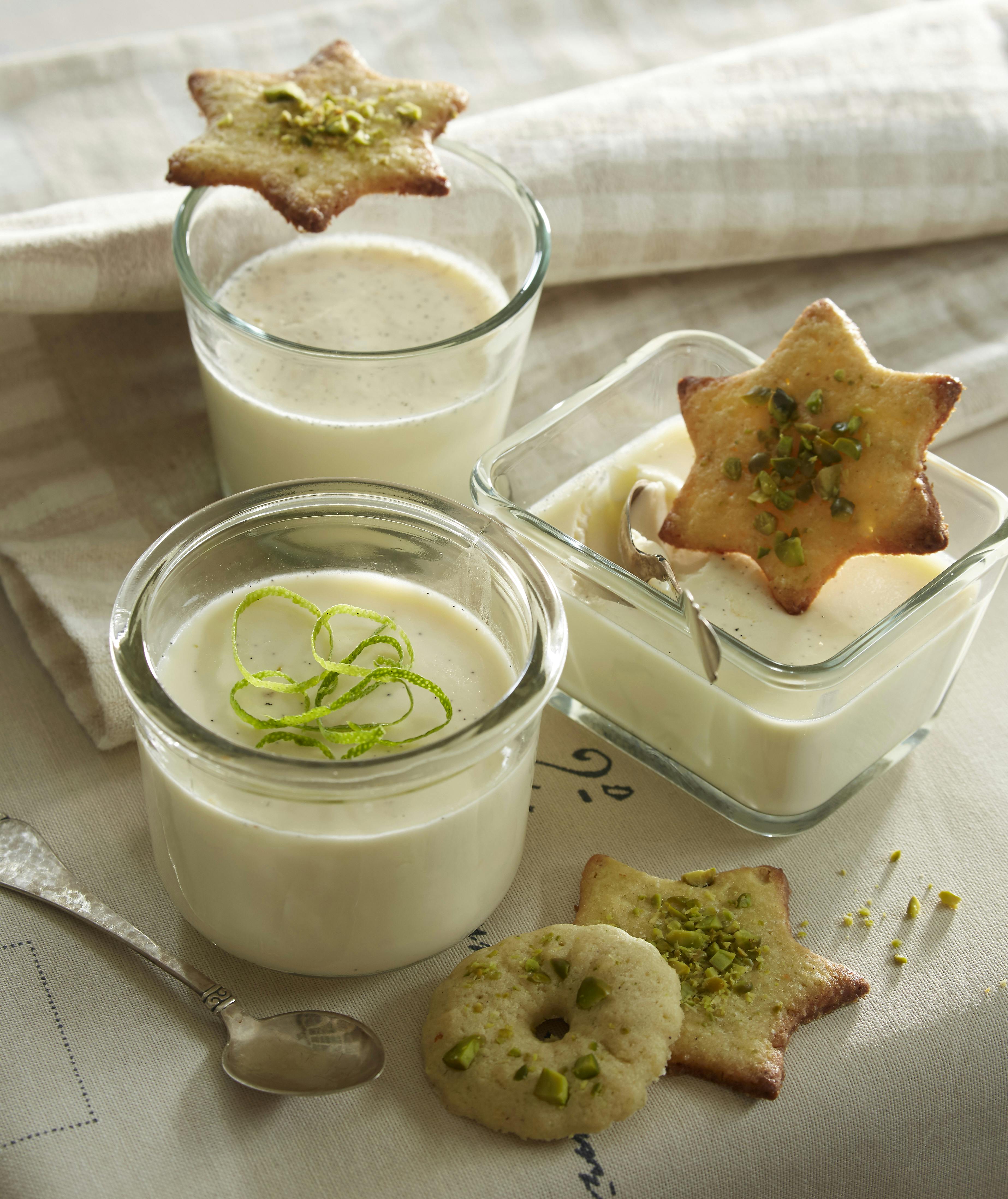 Pannacotta med lime og vanilje serveret med strimler af limeskal og små kager med pistaciedrys