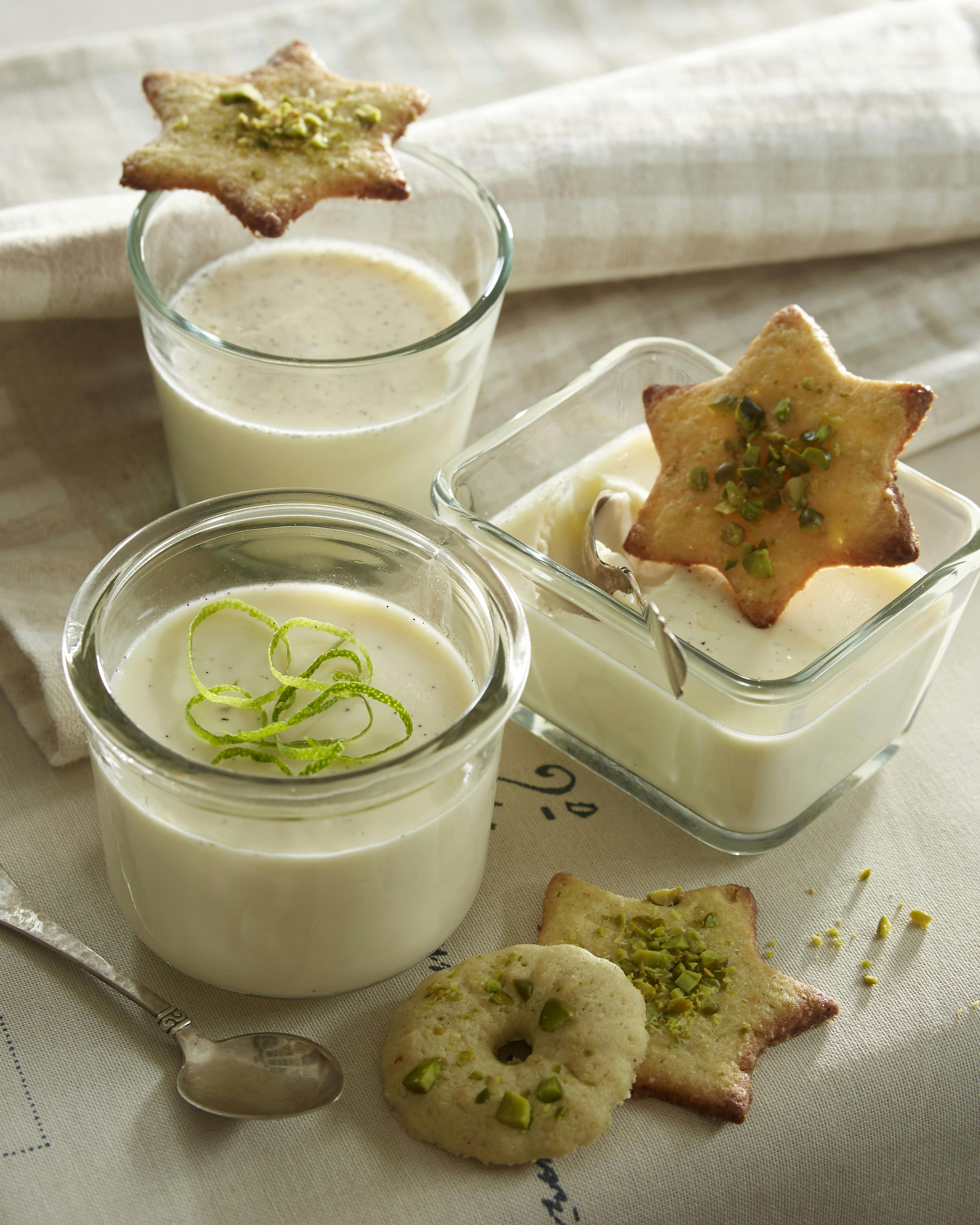 Pannacotta med lime og vanilje serveret med strimler af limeskal og små kager med pistaciedrys