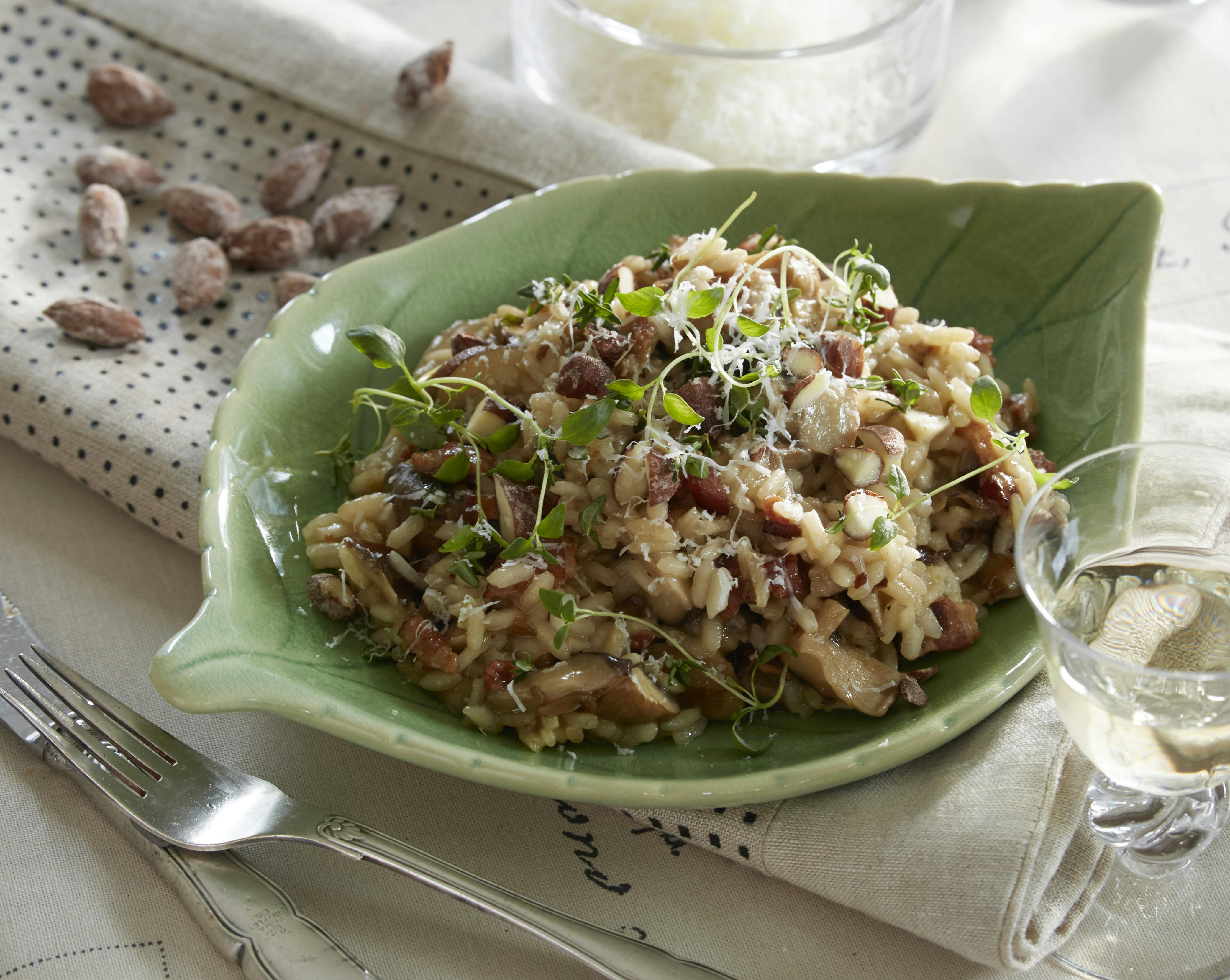 Risotto med ristede bacontern, blandede svampe og løg kogt med bouillon og hvidvin og smagt til med parmesan og citron. På toppen saltmandler