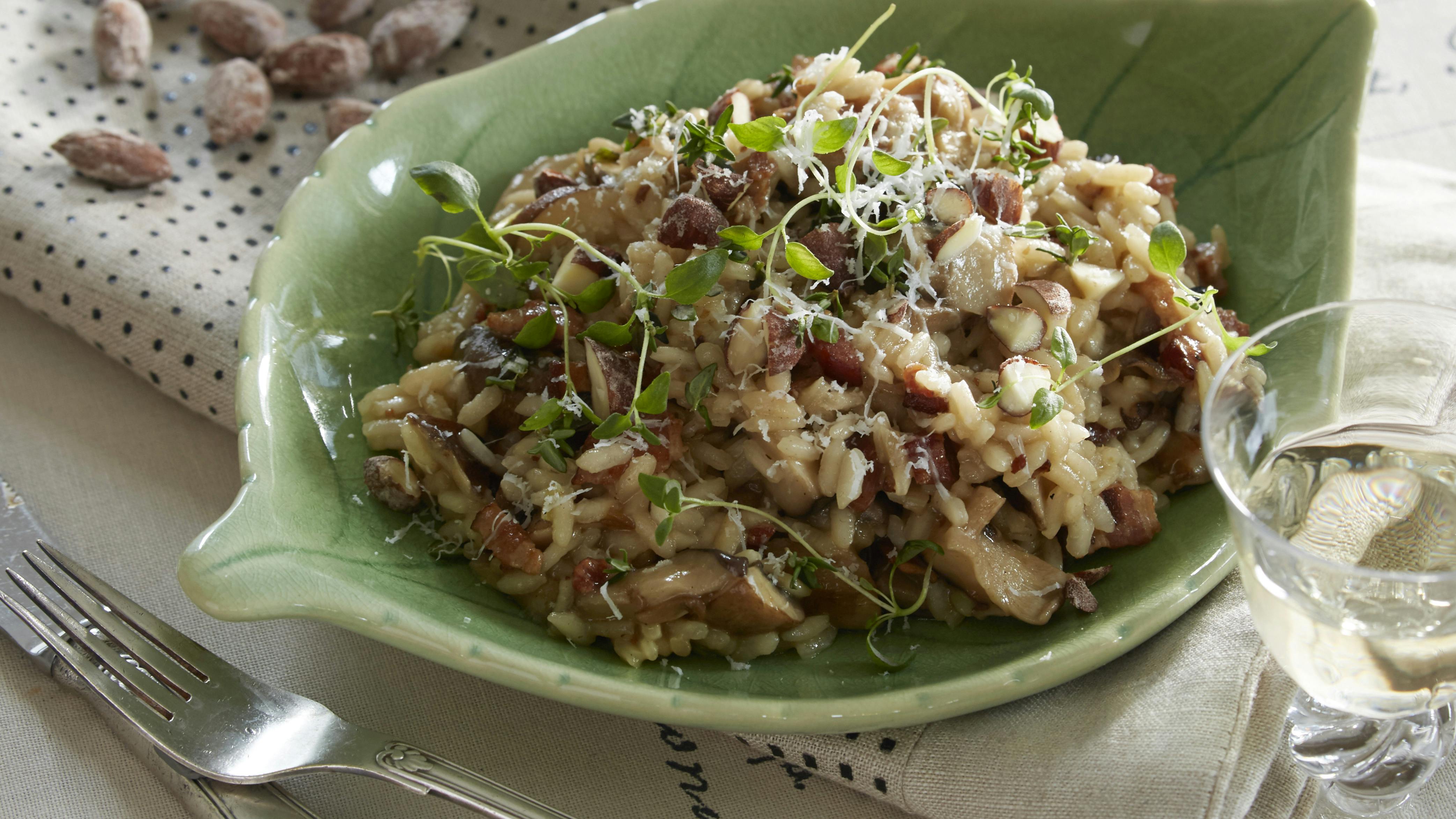 Risotto med ristede bacontern, blandede svampe og løg kogt med bouillon og hvidvin og smagt til med parmesan og citron. På toppen saltmandler