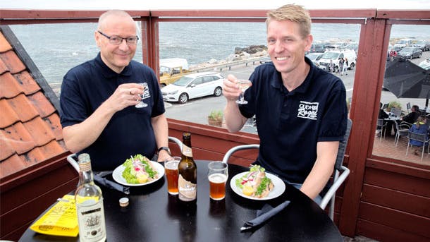 To mænd spiser Sol over Gudhjem på Gudhjem røgeri