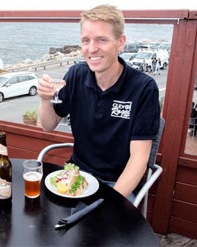 To mænd spiser Sol over Gudhjem på Gudhjem røgeri