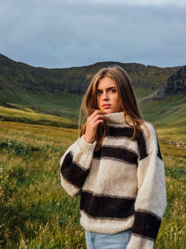 Dame står med strikket sweater med høj hals