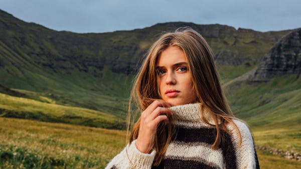 Dame står med strikket sweater med høj hals