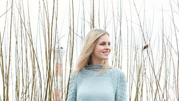 Dame står med striksweater på