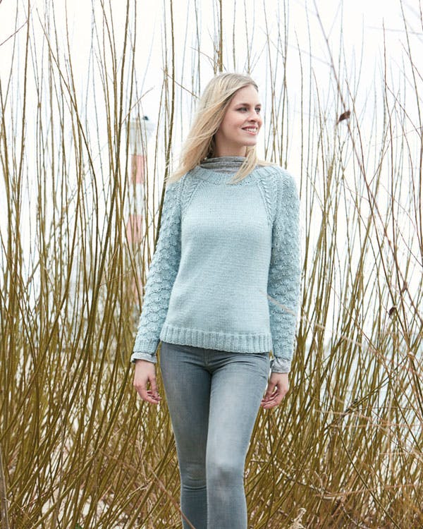 Dame står med striksweater på