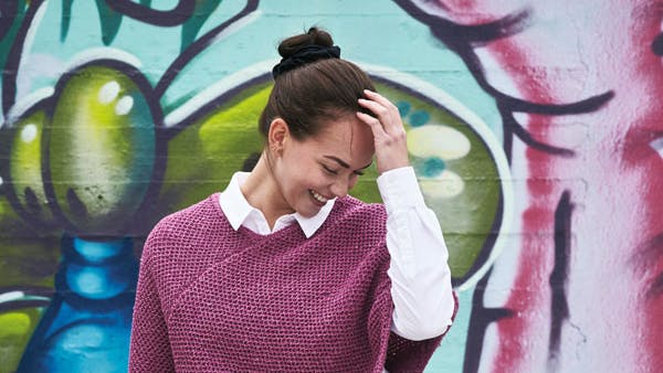Dame i rosa poncho i netpatent. Strikkeopskrift