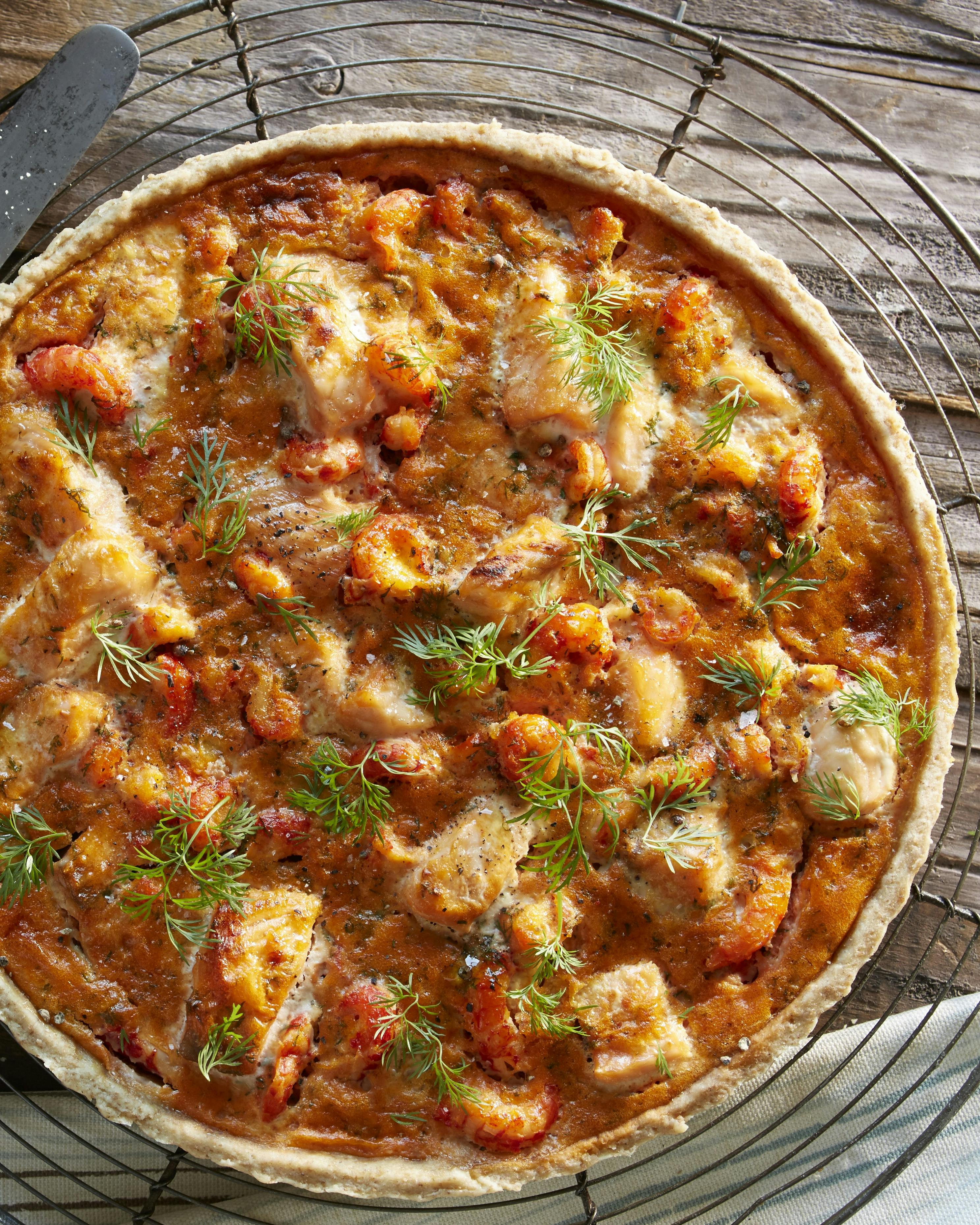 Tærte bagt med grahamsmel og med fyld af krebsehaler, laks, hvidløg. Tærten er pyntet med dild.