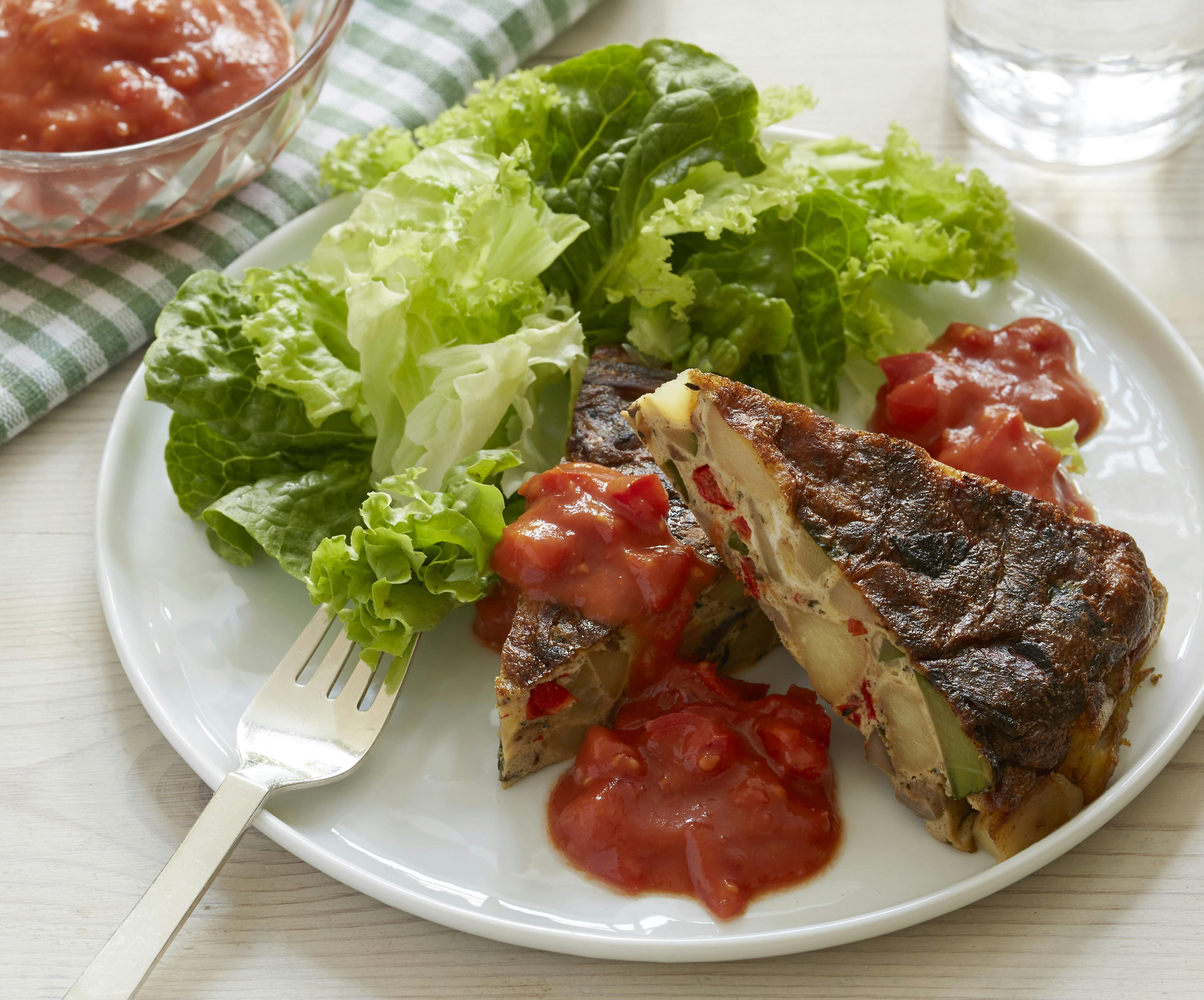 Pandestegt tortilla med kartoffel- og courgettestykker serveret med tomatsala og grøn salat