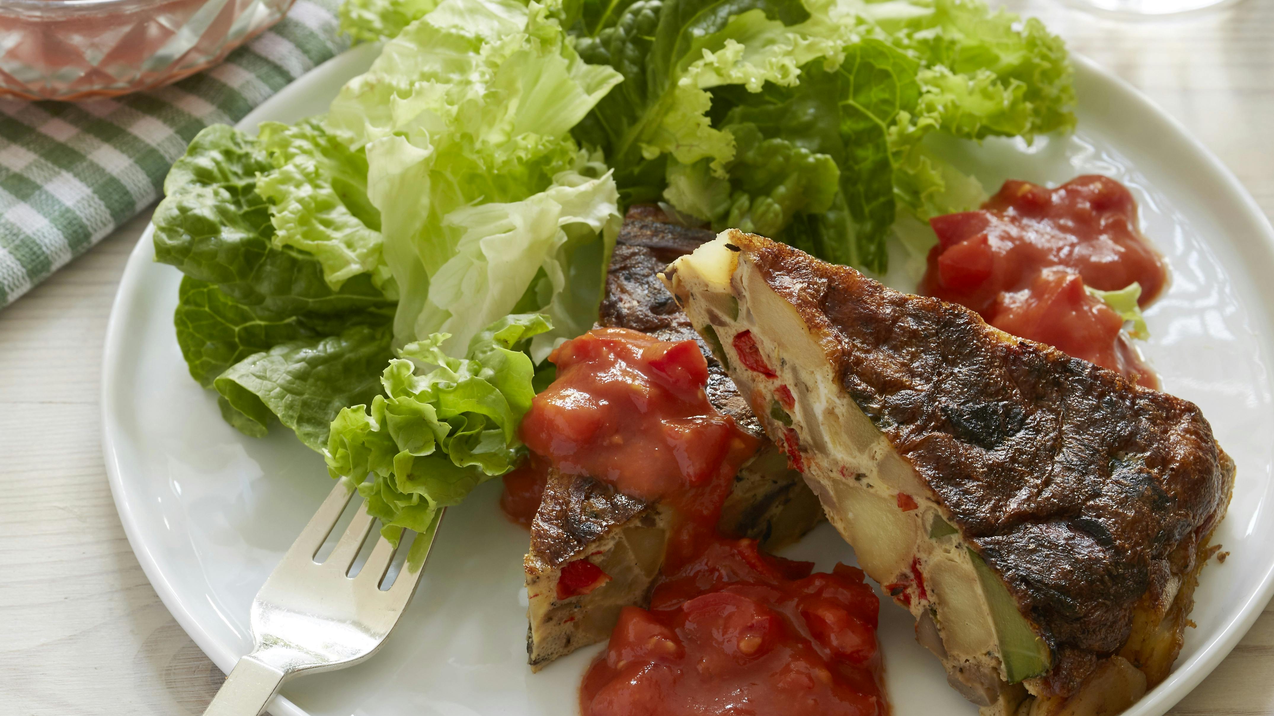 Pandestegt tortilla med kartoffel- og courgettestykker serveret med tomatsala og grøn salat