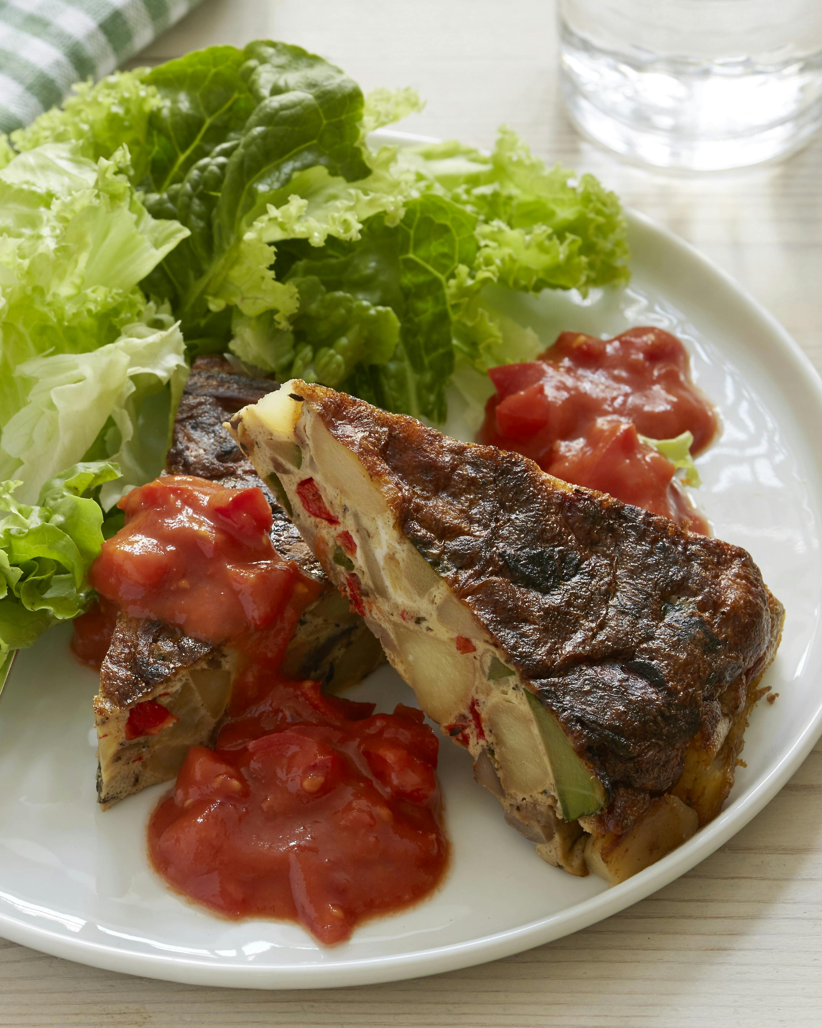 Pandestegt tortilla med kartoffel- og courgettestykker serveret med tomatsala og grøn salat