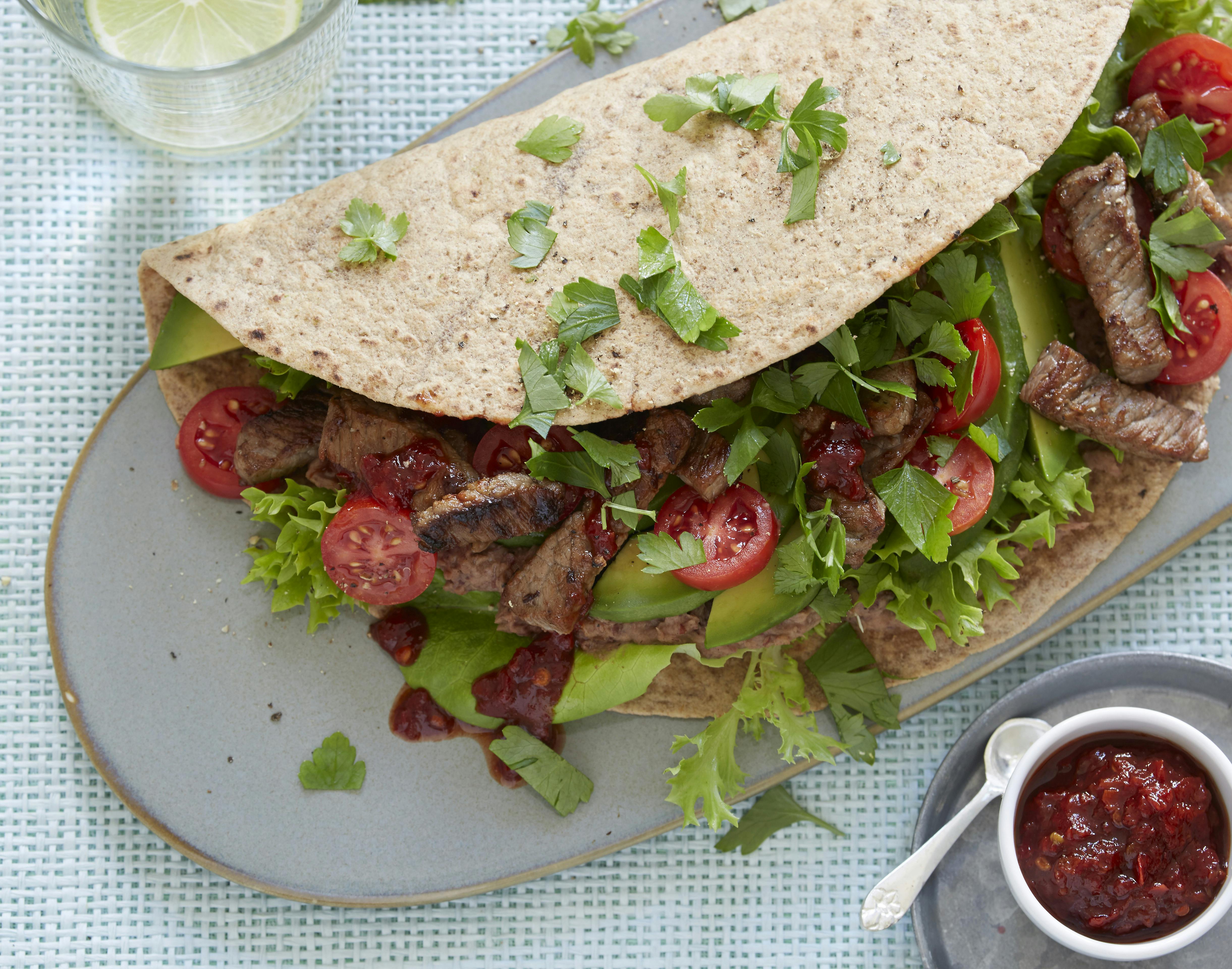Tortillawraps smurt med bønnecreme og fyldt med strimler af ristet oksekød, salat, tomat, avocado og persille. Hertil chilisauce.