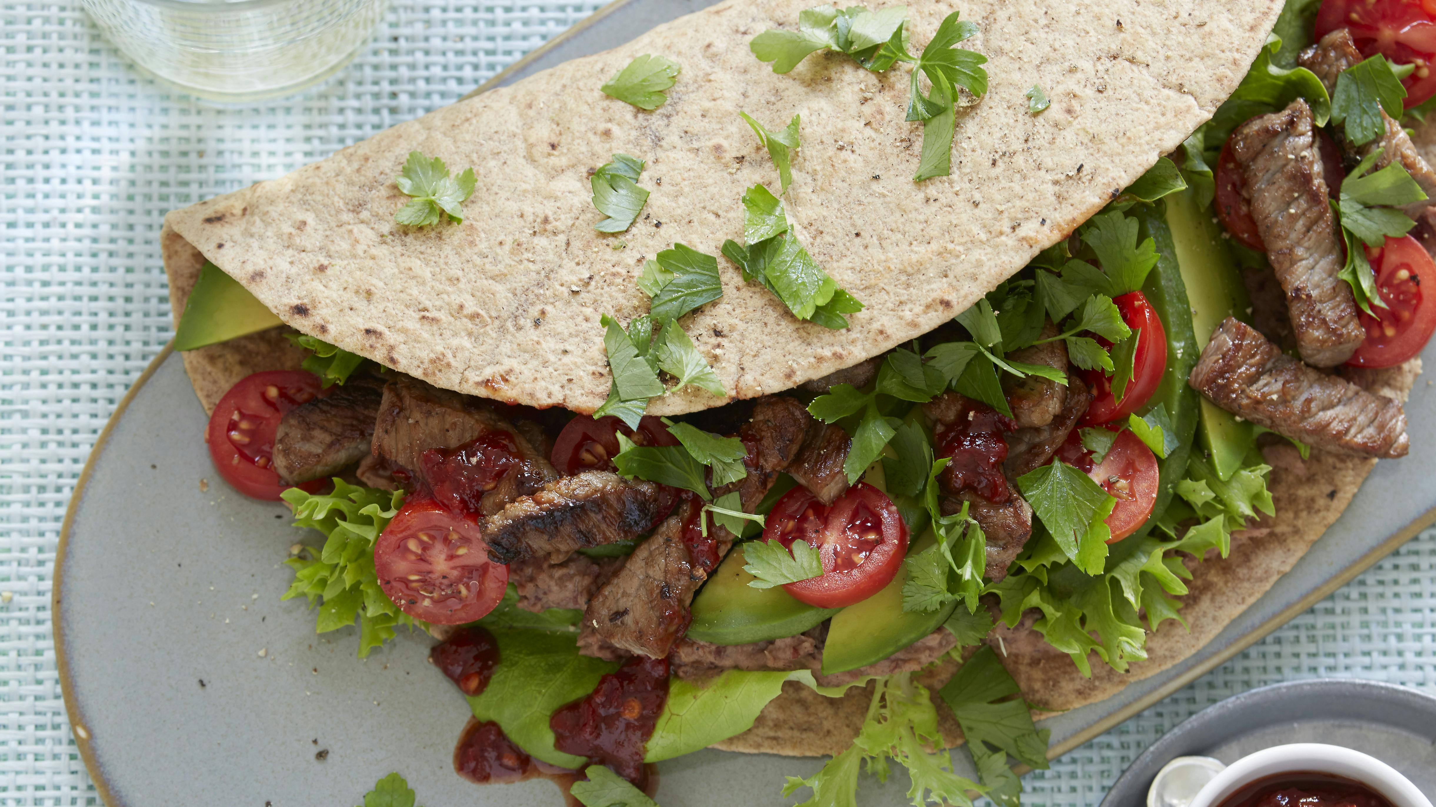 Tortillawraps smurt med bønnecreme og fyldt med strimler af ristet oksekød, salat, tomat, avocado og persille. Hertil chilisauce.