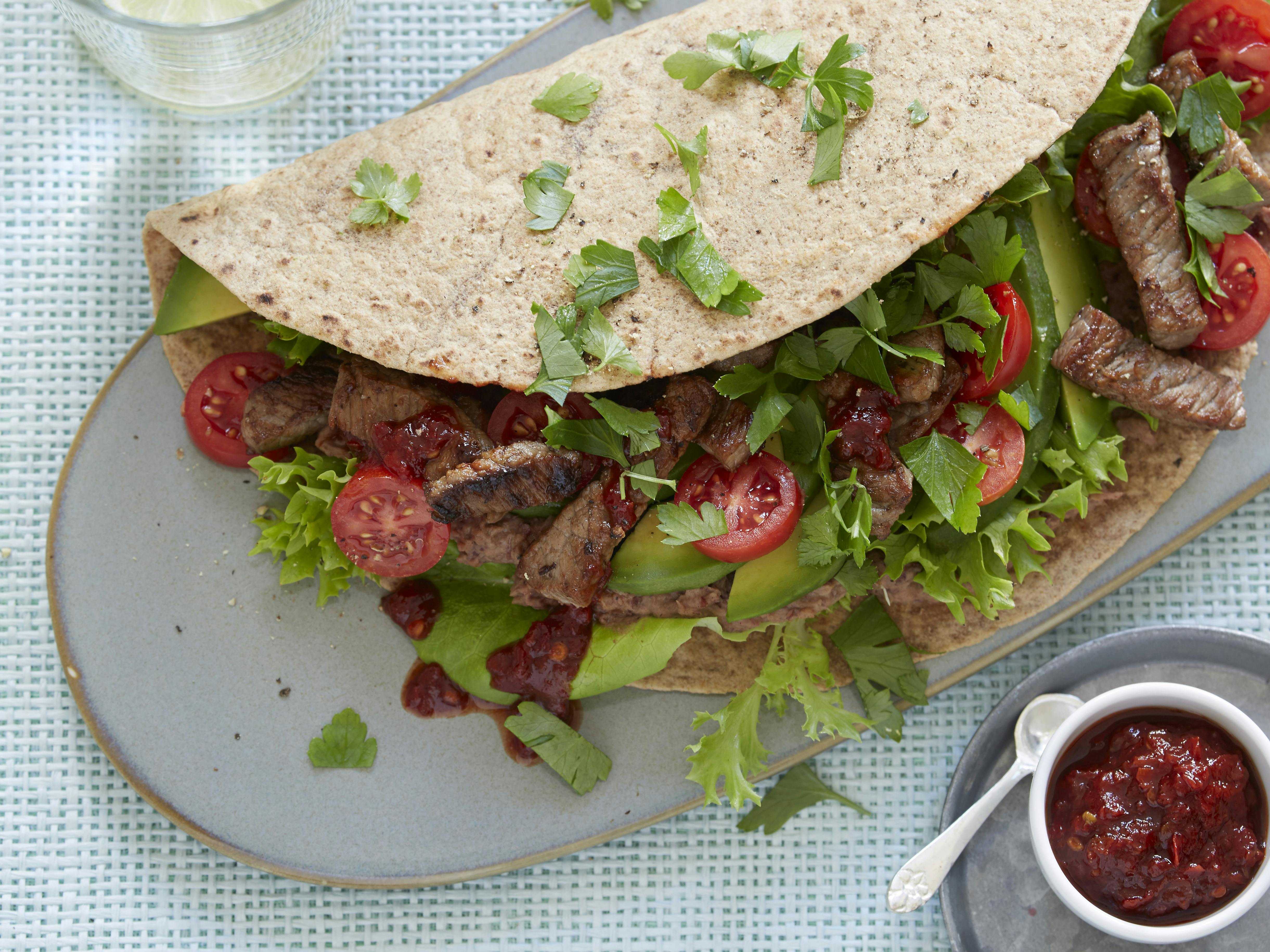 Tortillawraps smurt med bønnecreme og fyldt med strimler af ristet oksekød, salat, tomat, avocado og persille. Hertil chilisauce.