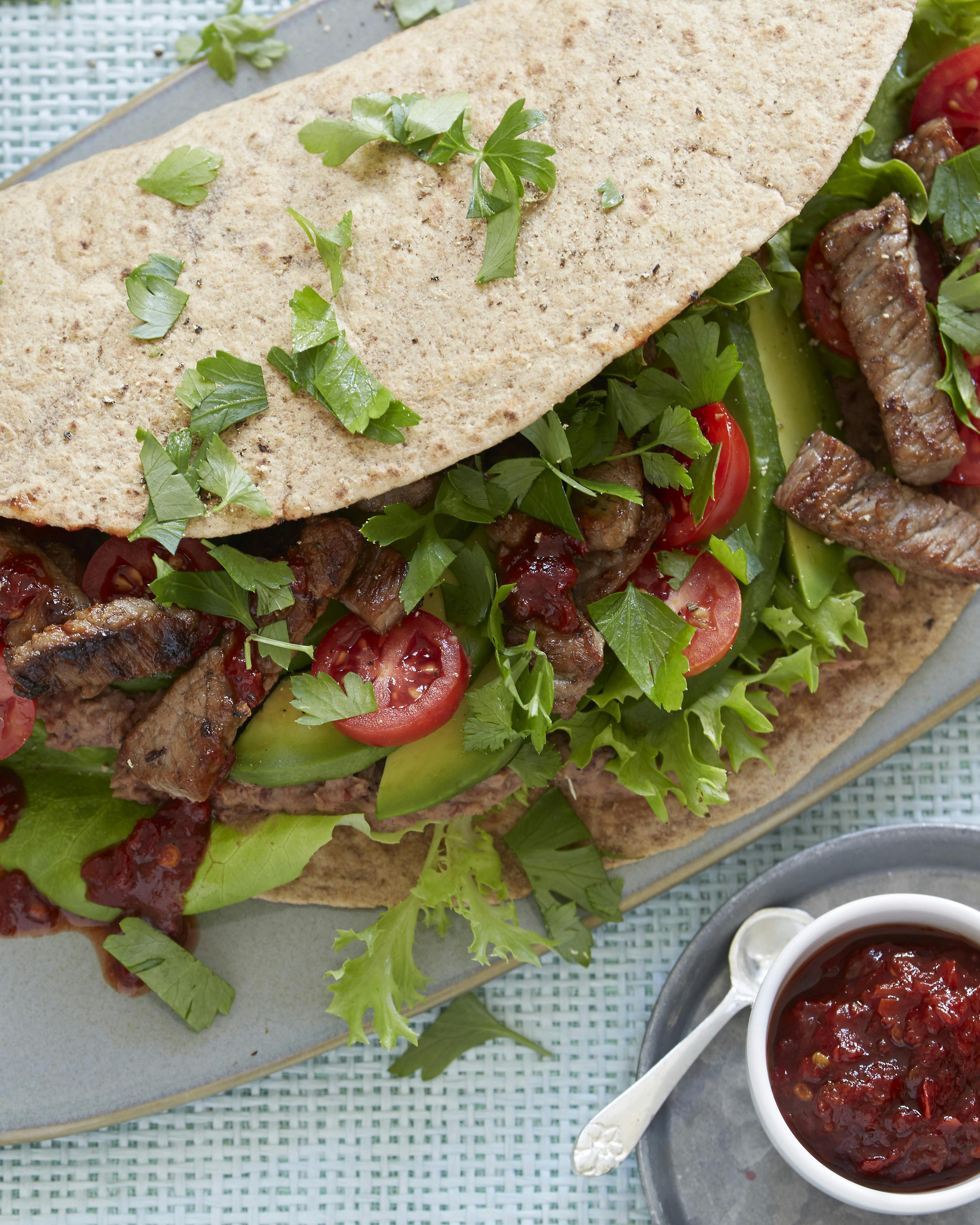 Tortillawraps smurt med bønnecreme og fyldt med strimler af ristet oksekød, salat, tomat, avocado og persille. Hertil chilisauce.