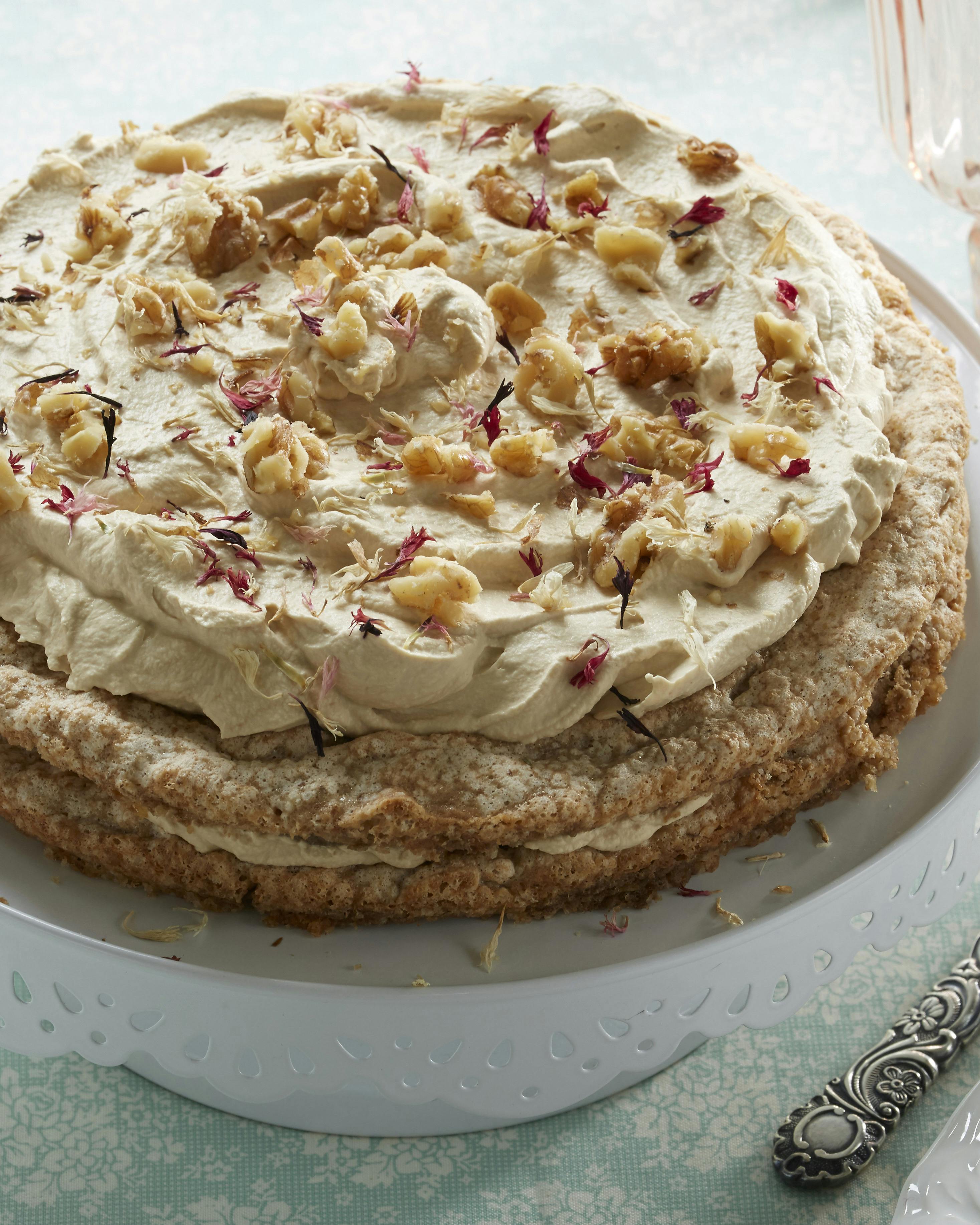 Valnøddekage lavet af to marengsbunde med et lag mokkaflødeskum imellem og på toppen og med drys af hakkede valnødder