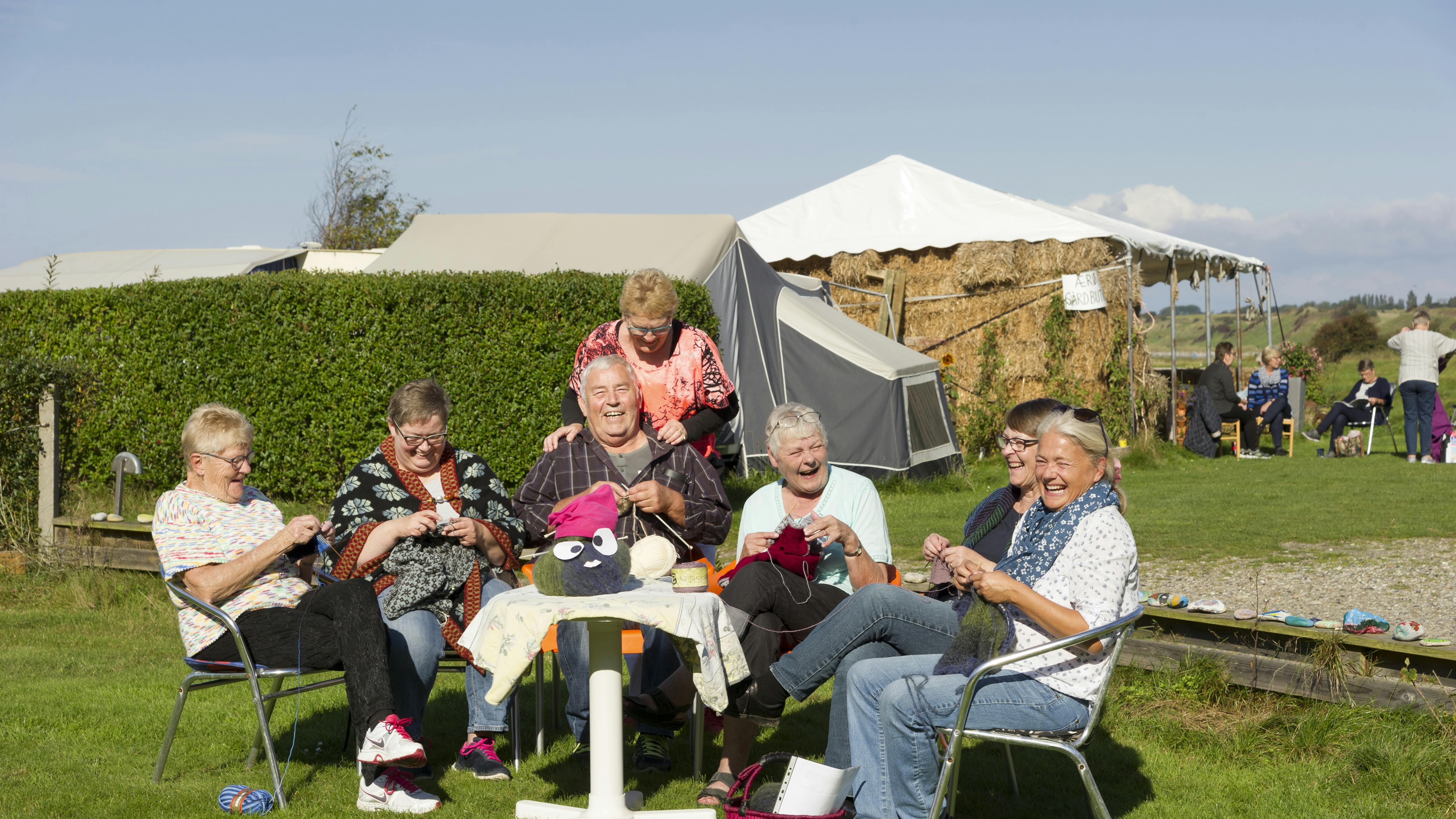 En gruppe mennesker sidder på en campingplads for at strikke sammen