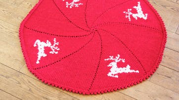 Strikket, rødt juletræstæppe med rensdyr